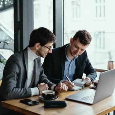 Two people reviewing documents beside a laptop